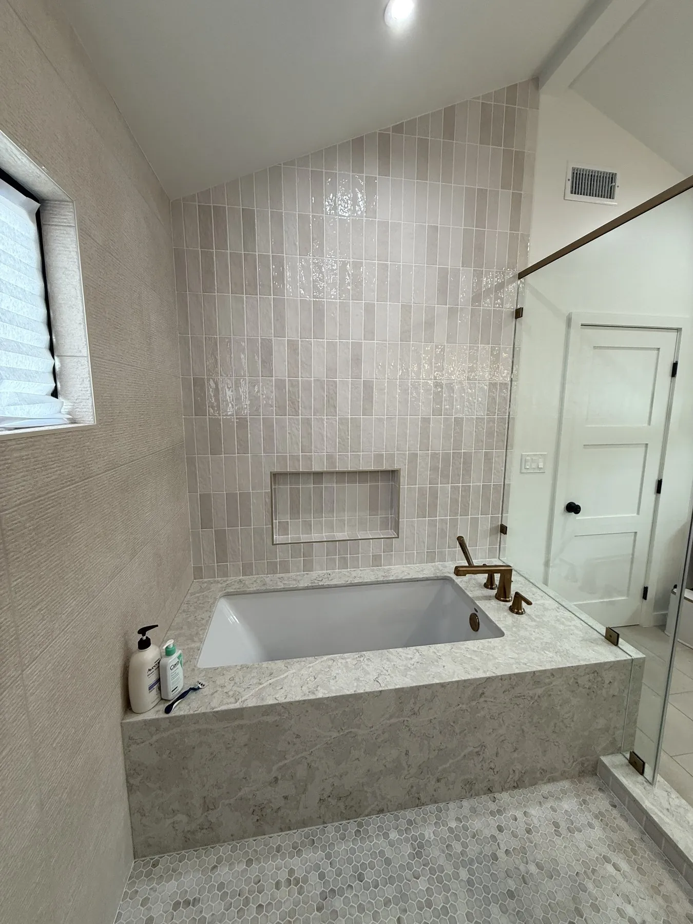 Curbless walk-in shower and freestanding tub sharing a single wet zone